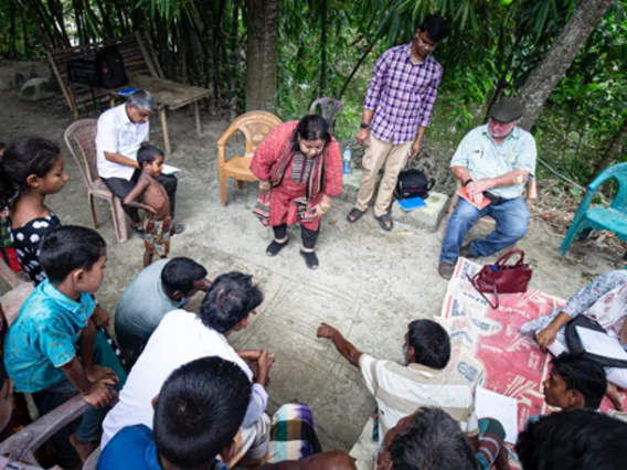 People gathered in a circle mapping out building plans in the dirt