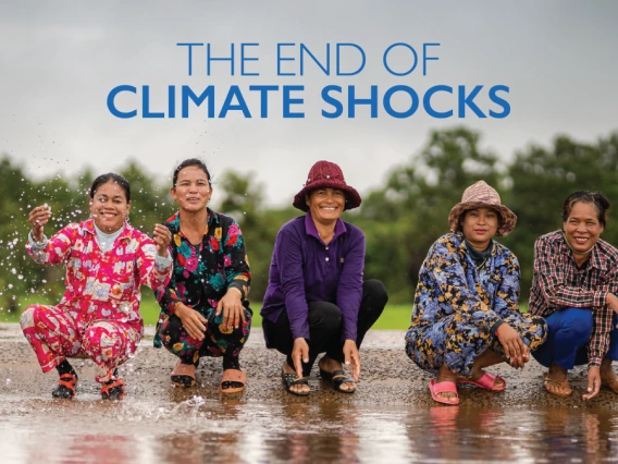 People smiling and lightly playing in a stream of water, text reads: The End of Climate Shocks