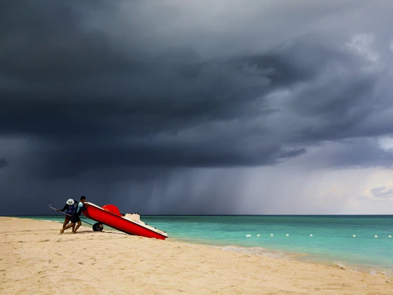 Two men on a beach pushing a board into the water