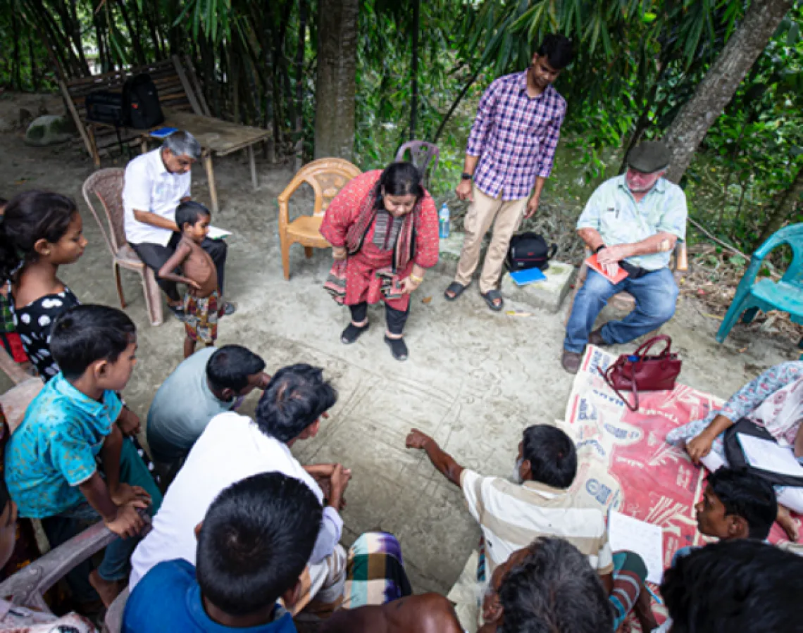 People gathered in a circle mapping out building plans in the dirt