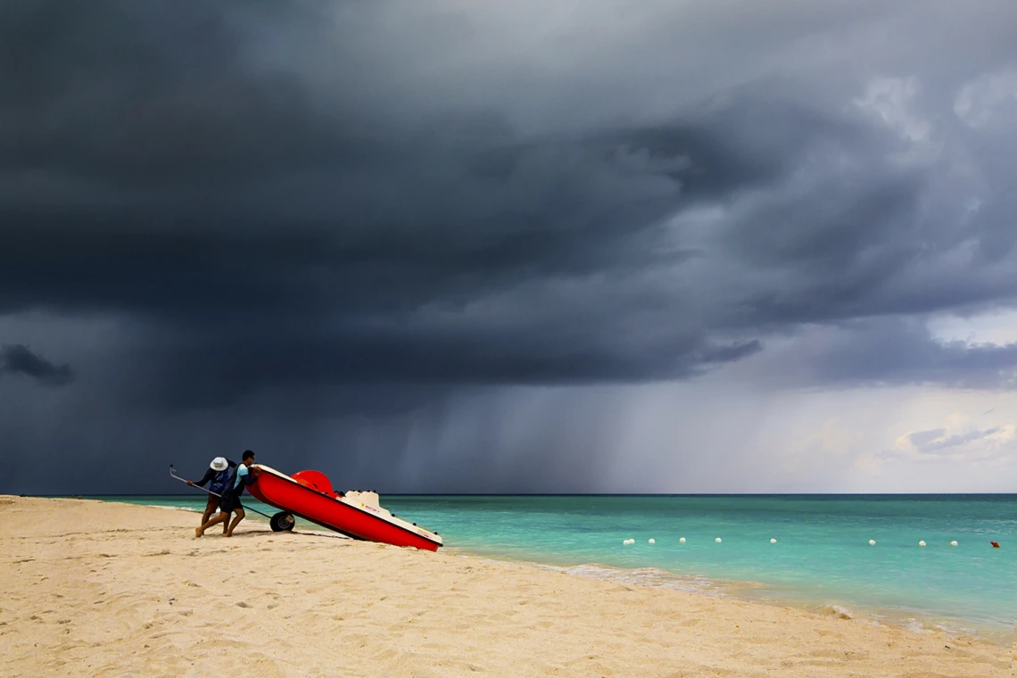 Two men on a beach pushing a board into the water